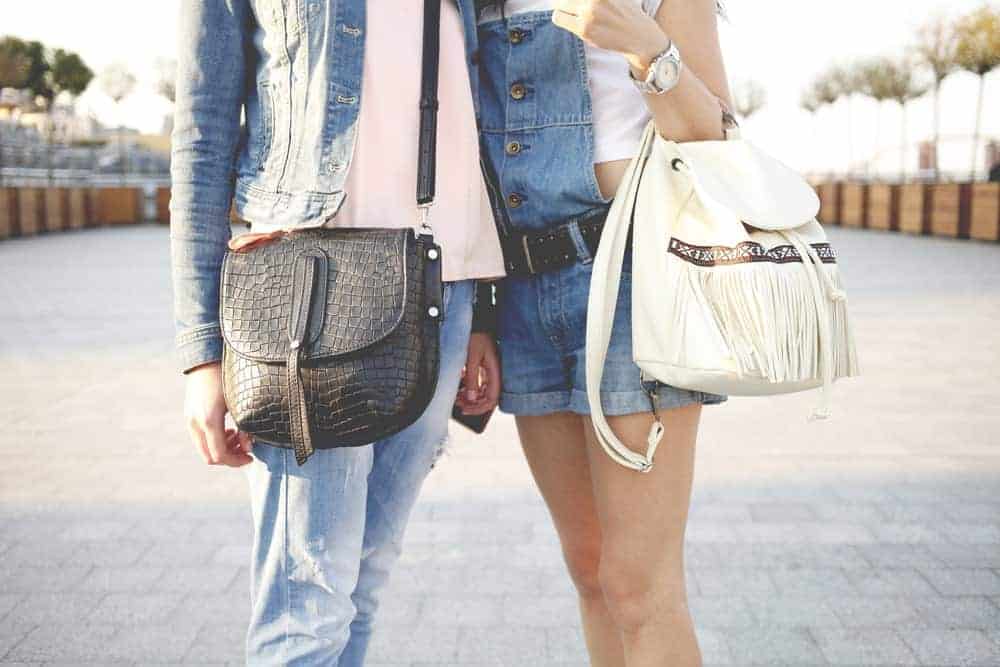 A close look at a couple of women carrying purses.