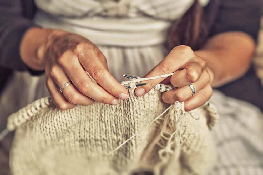A close look at a woman knitting with yarn.