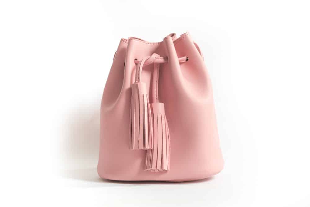 A pink leather bucket bag with tussles.
