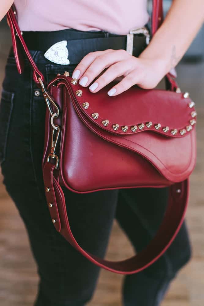 A woman sporting a red leather crossbody purse.