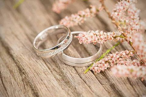A close look at wedding bands on a wooden table.