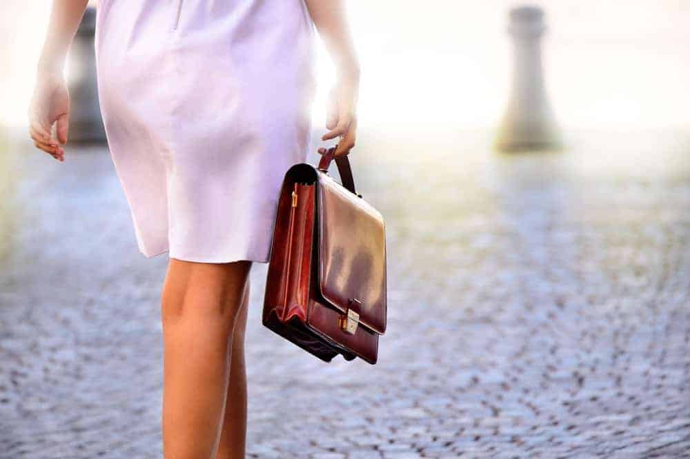 A woman heading to work carrying a brown leather portfolio bag.