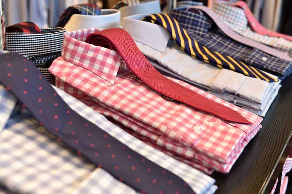 Sets of dress shirts without pockets and neckties on display at a store.