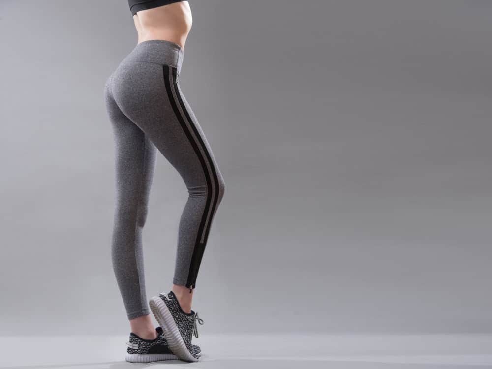 A close look at a woman wearing a pair of sporty gray leggings.