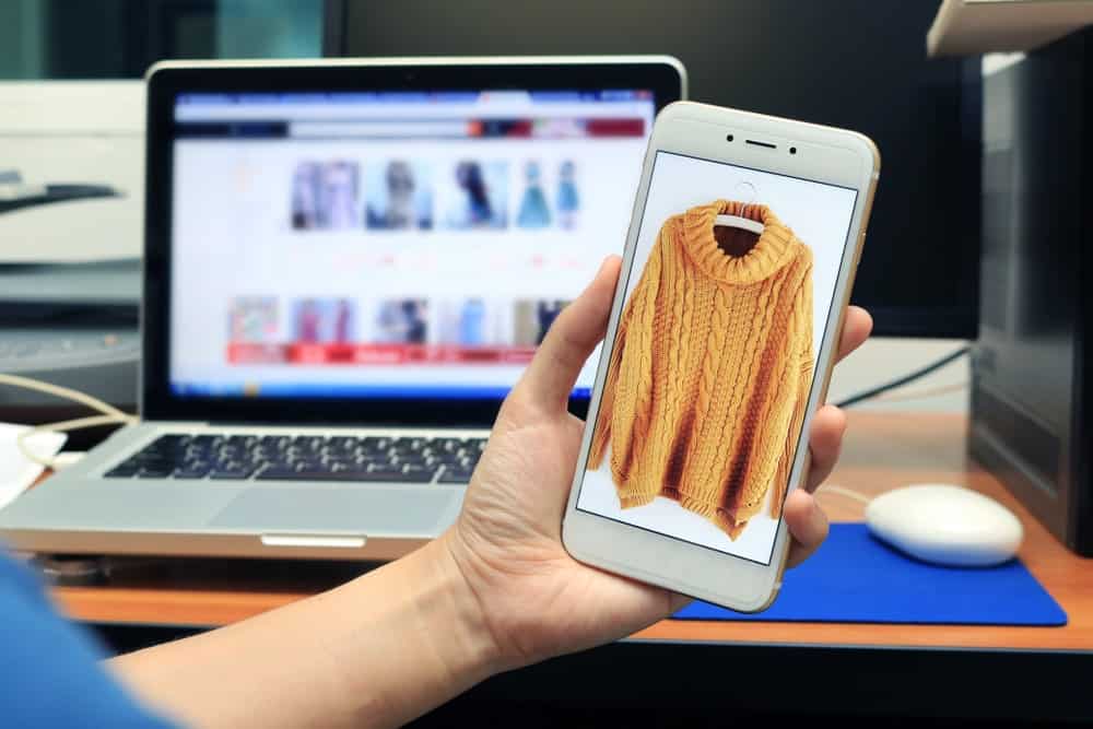 A mobile phone showcasing the sweater for sale in an online shop.