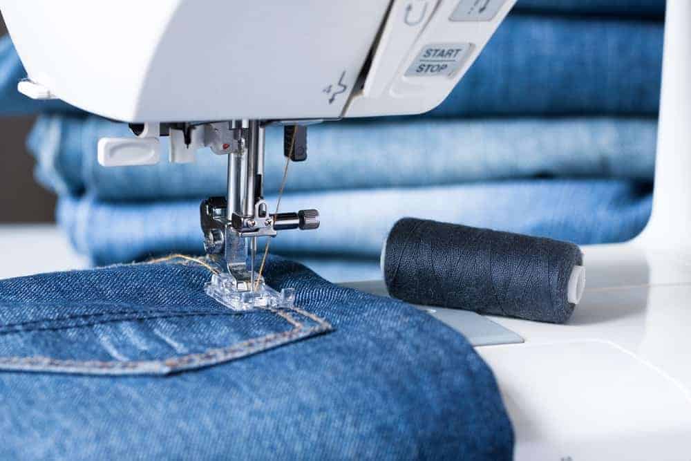A close look at a pair of jeans being sewn with a machine.