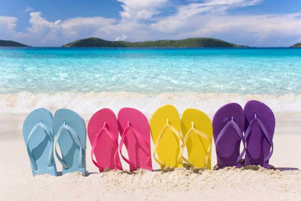 A row of colorful flip flops on a sandy beach.