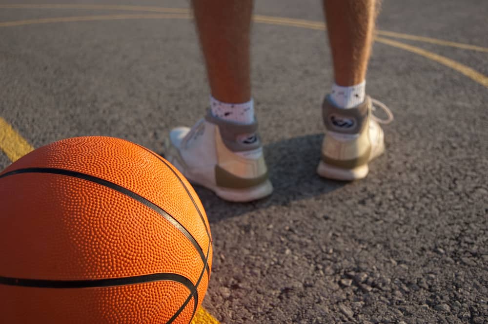 Orange basketball and player's legs on an outdoor court.