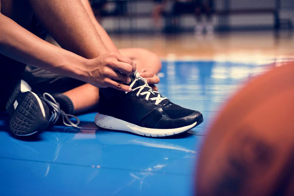Player tying his shoe laces on a basketball court.