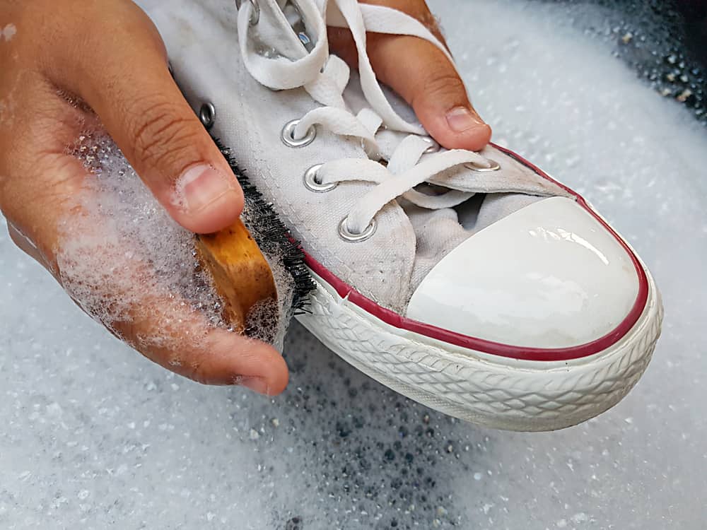 Cleaning white sneaker with soapy water.