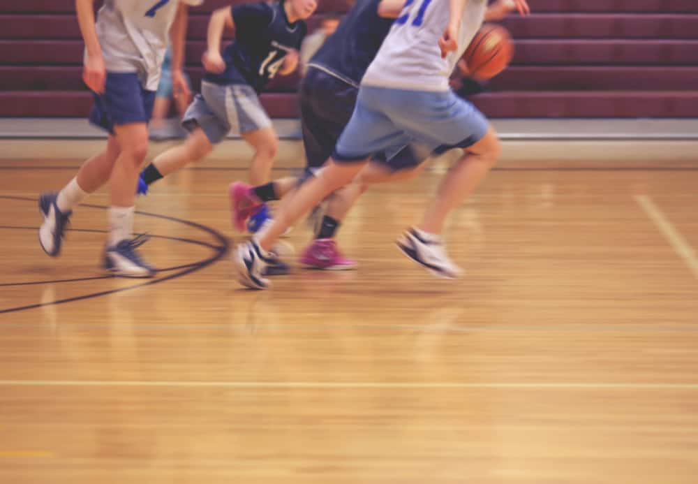 Team running down the court during basketball game.