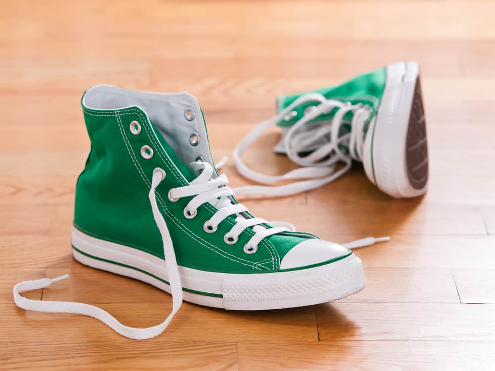 Green high cut sneakers on wooden floor.