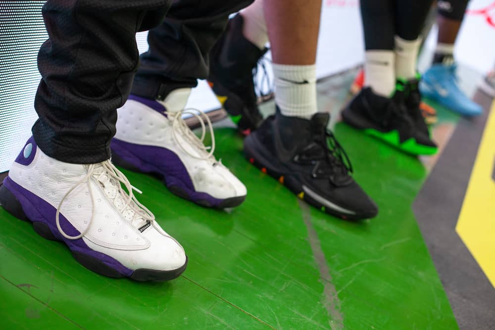 Jordan 13 Retro Lakers basketball shoes on parquet floor during a professional match.