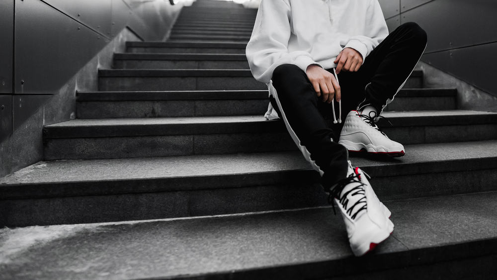 Man wearing basketball shoes sitting on stairs.