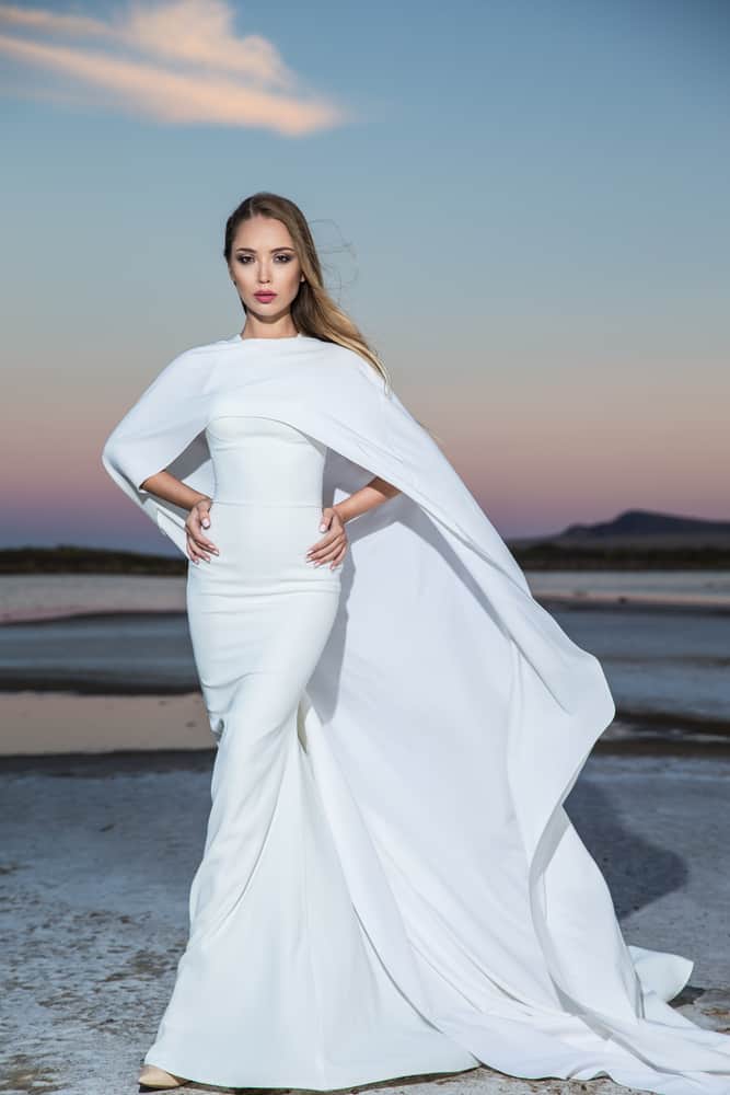 Model wearing a white cape dress.