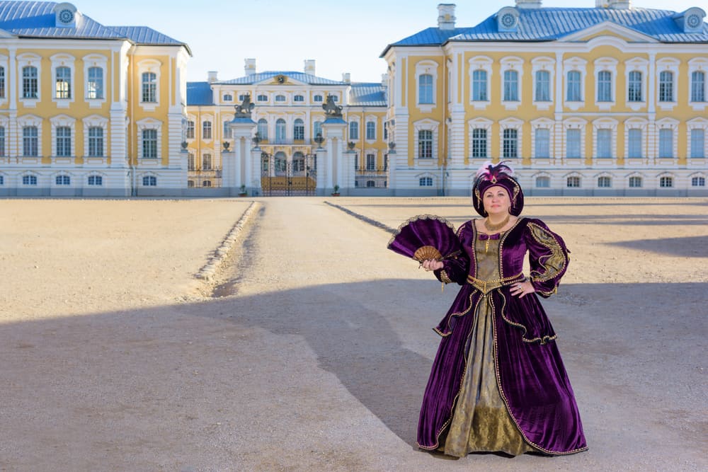 Woman near palace wearing a mantua dress.