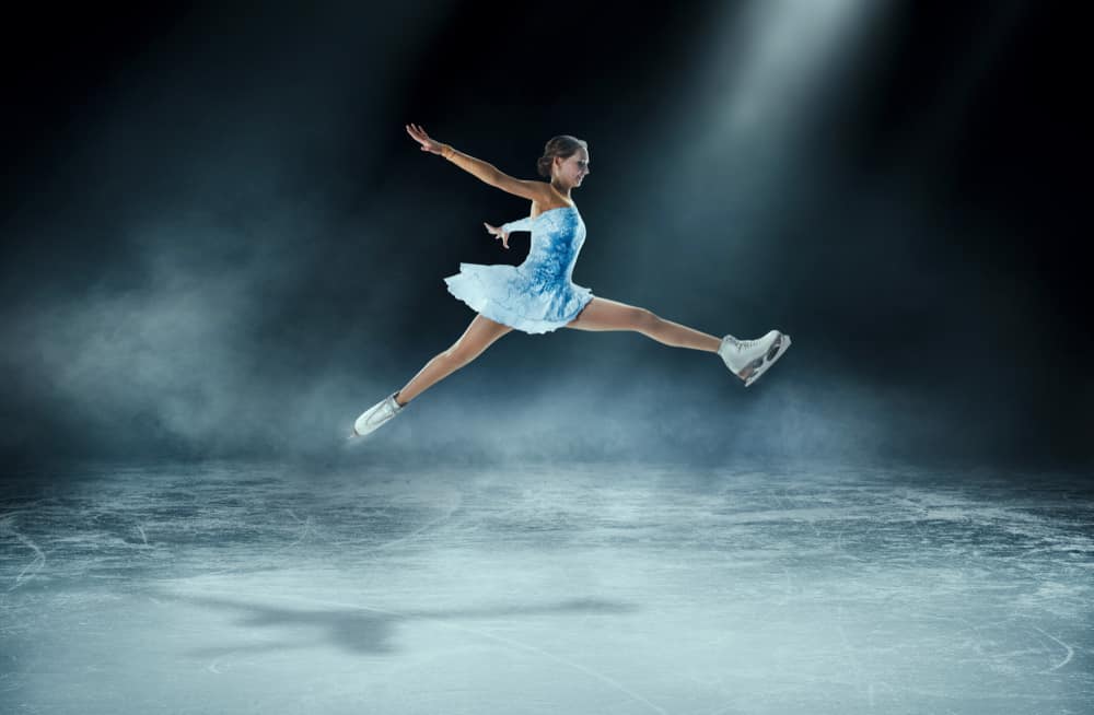 A girl figure skating in an ice arena.