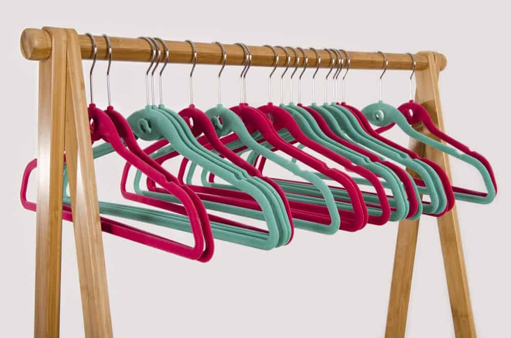 A row of velvet hangers on a wooden rack.