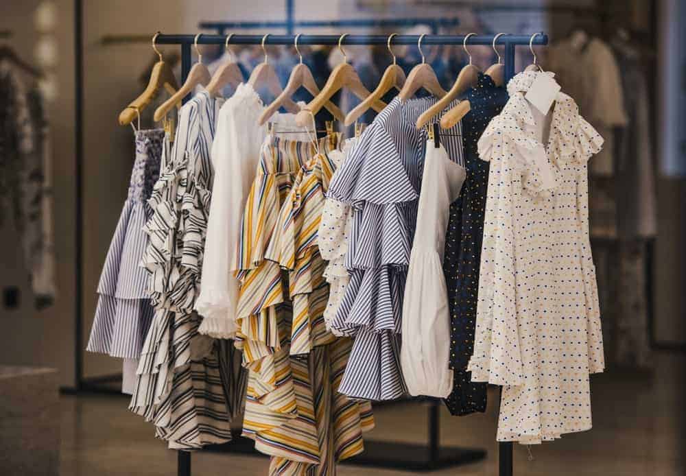 A rack of blouses supported by wooden dress hangers.