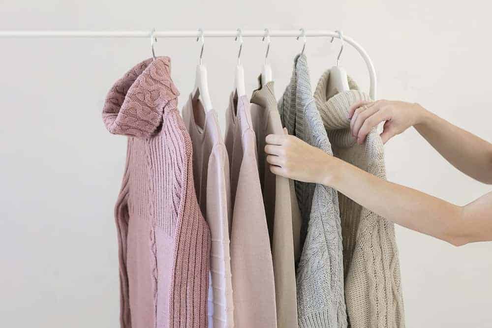 A variety of sweaters supported by sweater hangers.