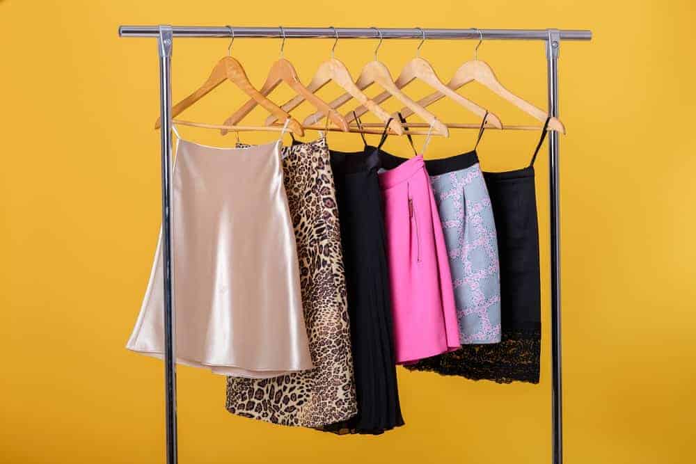 Colorful skirts hanging on wooden skirt hangers.