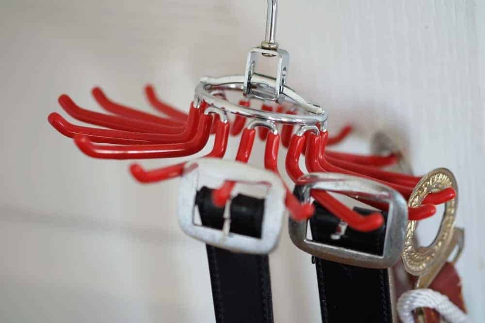 A red metal belt hanger supporting multiple belts.