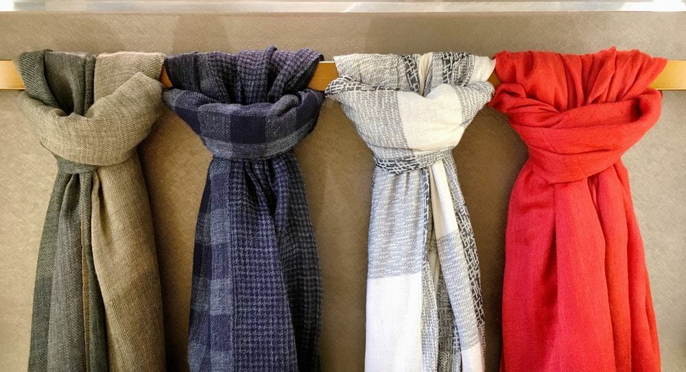 A row of scarves on a scarf hanger.