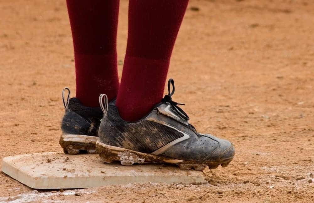 A close look at a baseball player wearing baseball shoes while standing on a base plate.