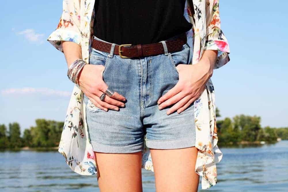 A close look at a woman wearing a pair of denim boyfriend shorts with her kimono.