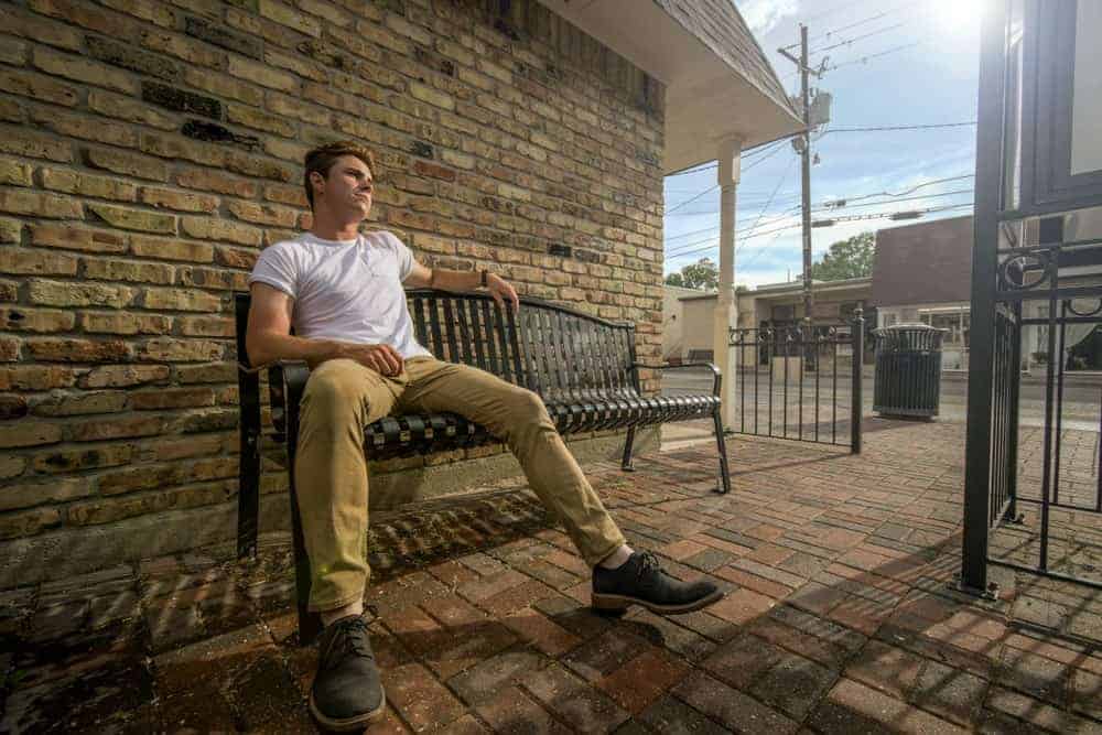 A man wearing a pair of khaki pants sitting on a bench.