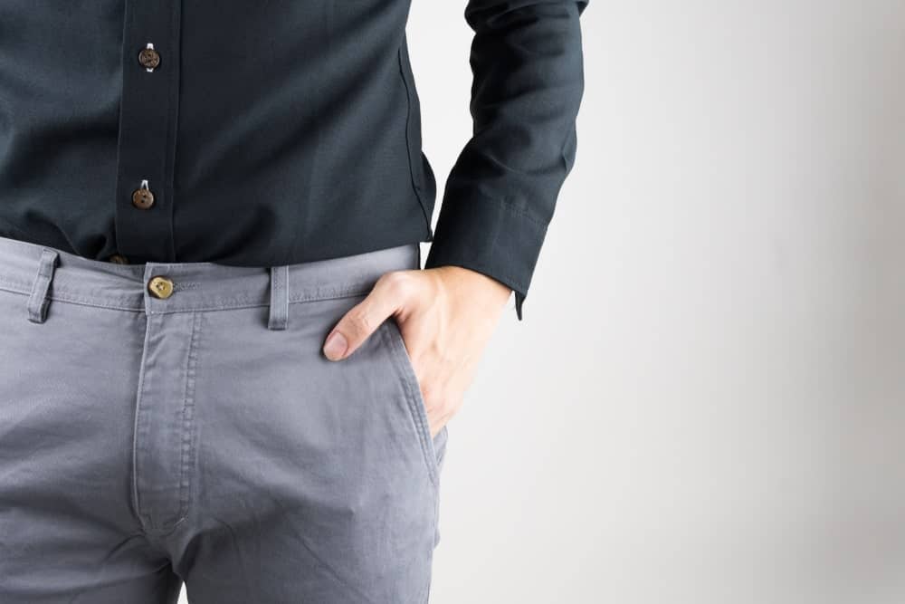 A close look at a man wearing a black button shirt and gray pants.