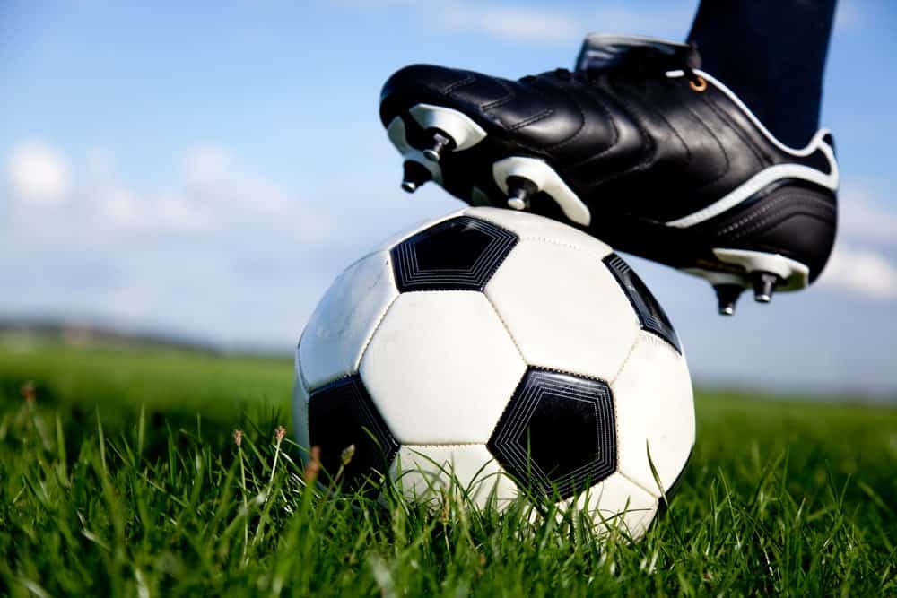 A close look at the foot of a soccer player with the shoes and the ball.
