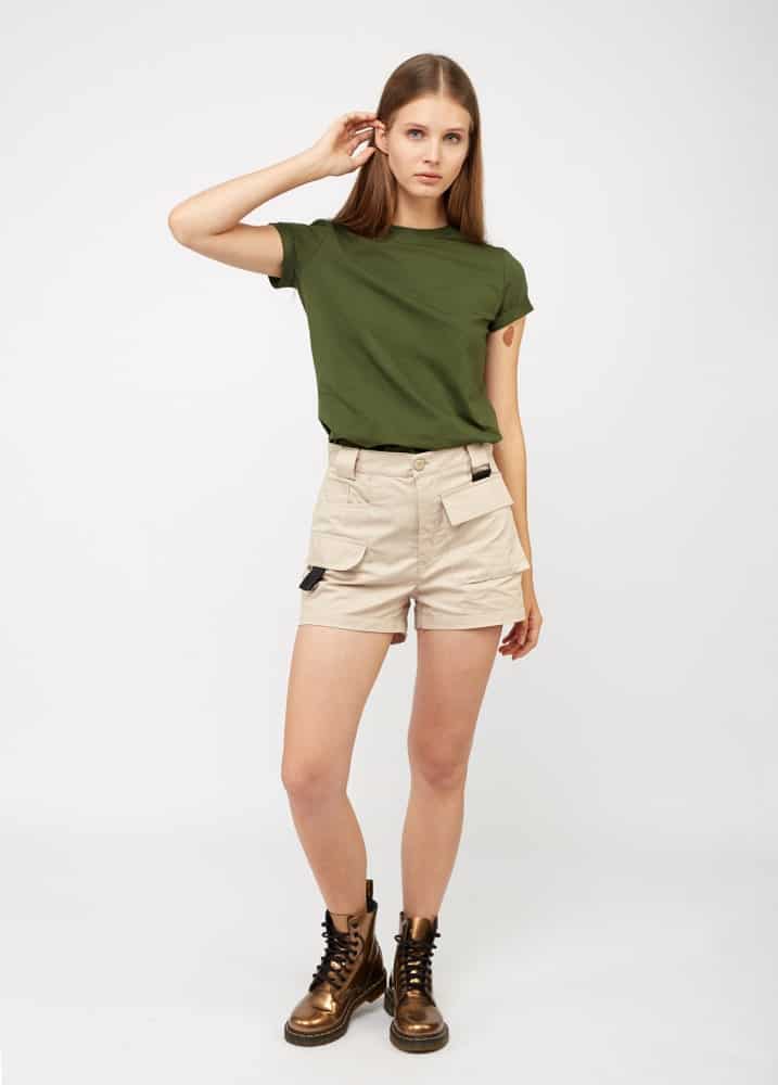 A woman wearing a pair of khaki shorts with boots.