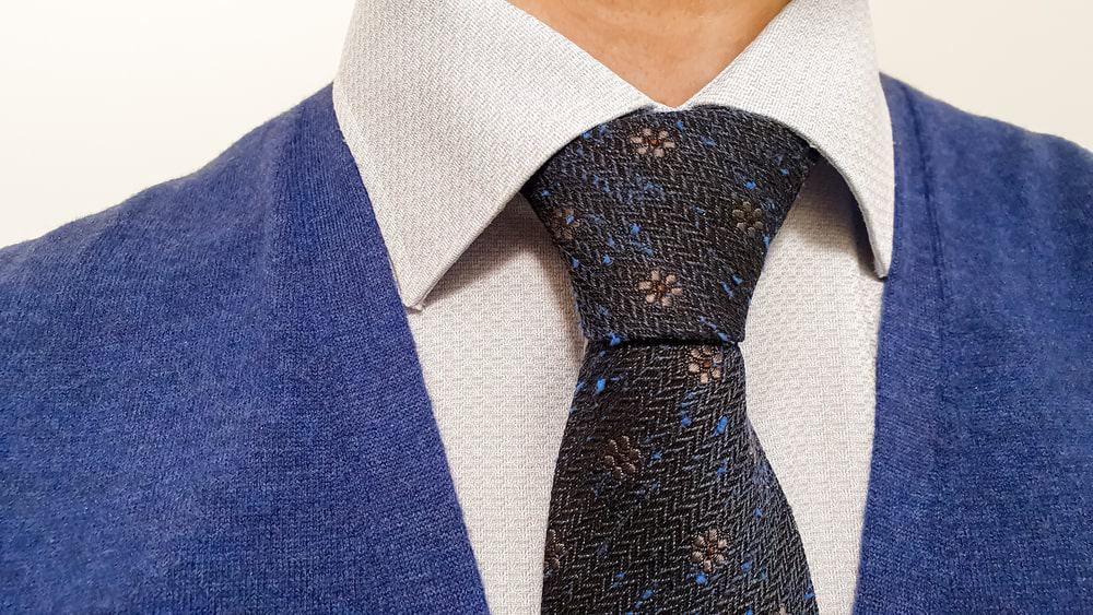 Marine blue tie with brown floral pattern in a half-Windsor knot.