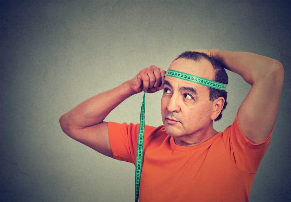 A man measuring the diameter of his head.