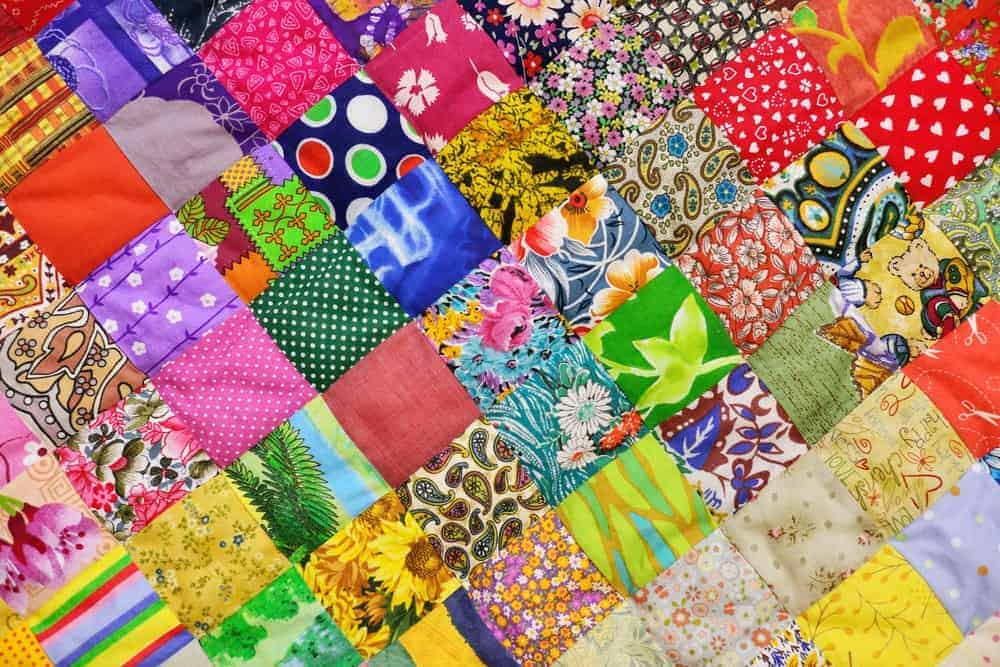 A close look at the colorful design and pattern of a one patch block quilt.