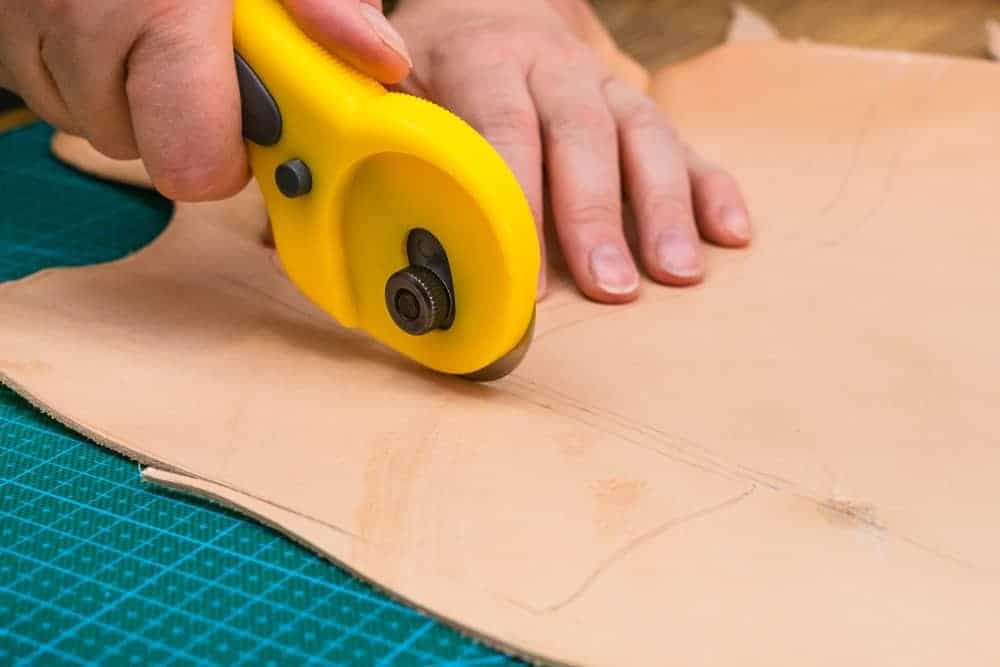 A rotary cutter being used to cut a material.