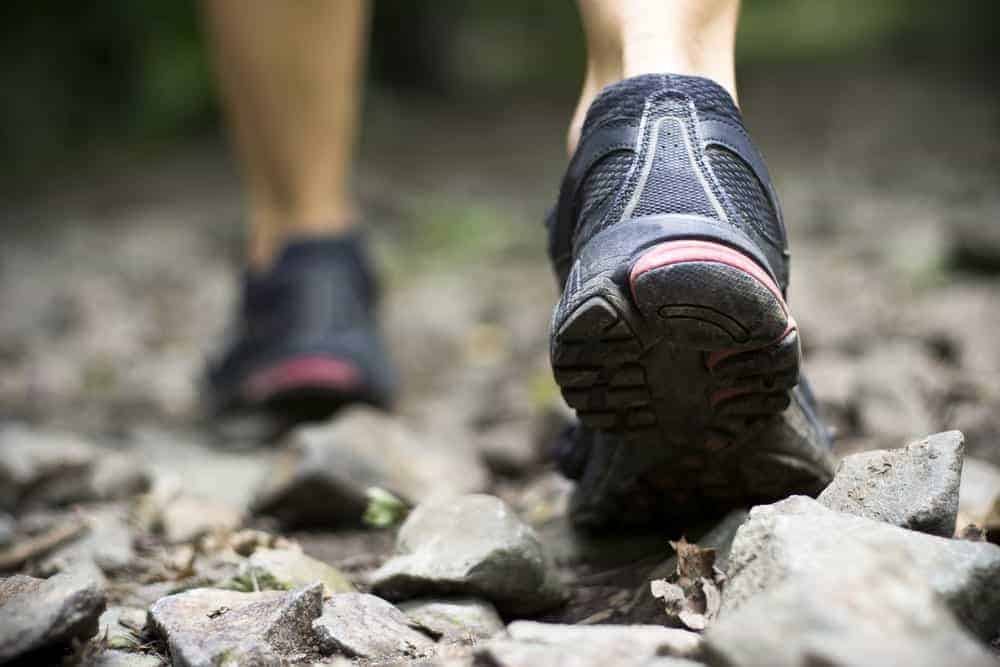 This is a close look at a woman hiking with running shoes on.