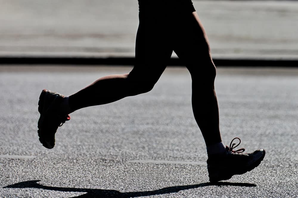 This is a close look at a woman running on an asphalt road.