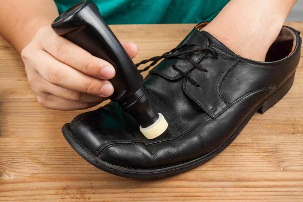 A man polishing a black shoe with liquid shoe polish.