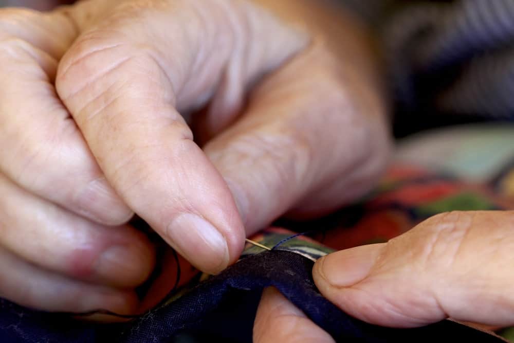 A close look at a pair of hands doing stitching on a piece of cloth.