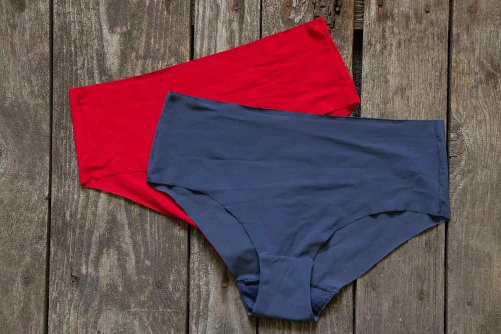 Red and blue seamless women's briefs on a wooden floor.