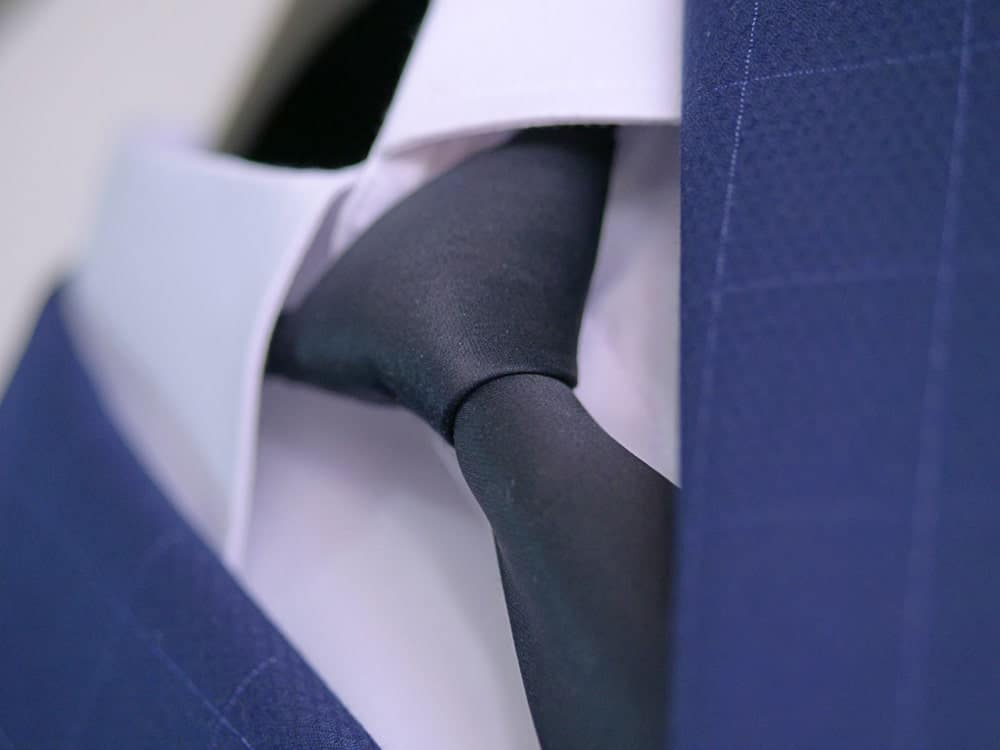 Navy blue suit with white shirt and embroidered silk necktie in Windsor knot.
