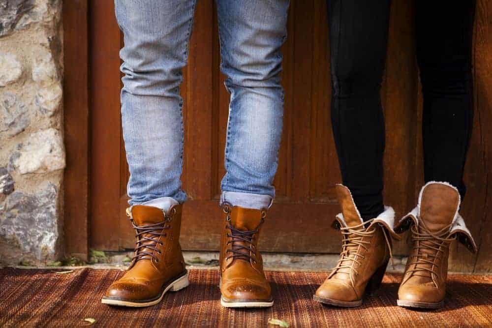 Couple's feet wearing brown leather boots.