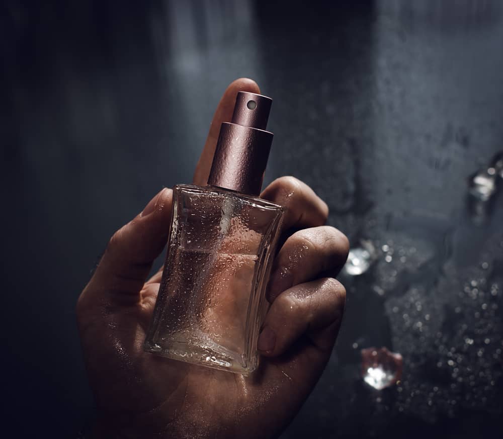 A hand holding a perfume.