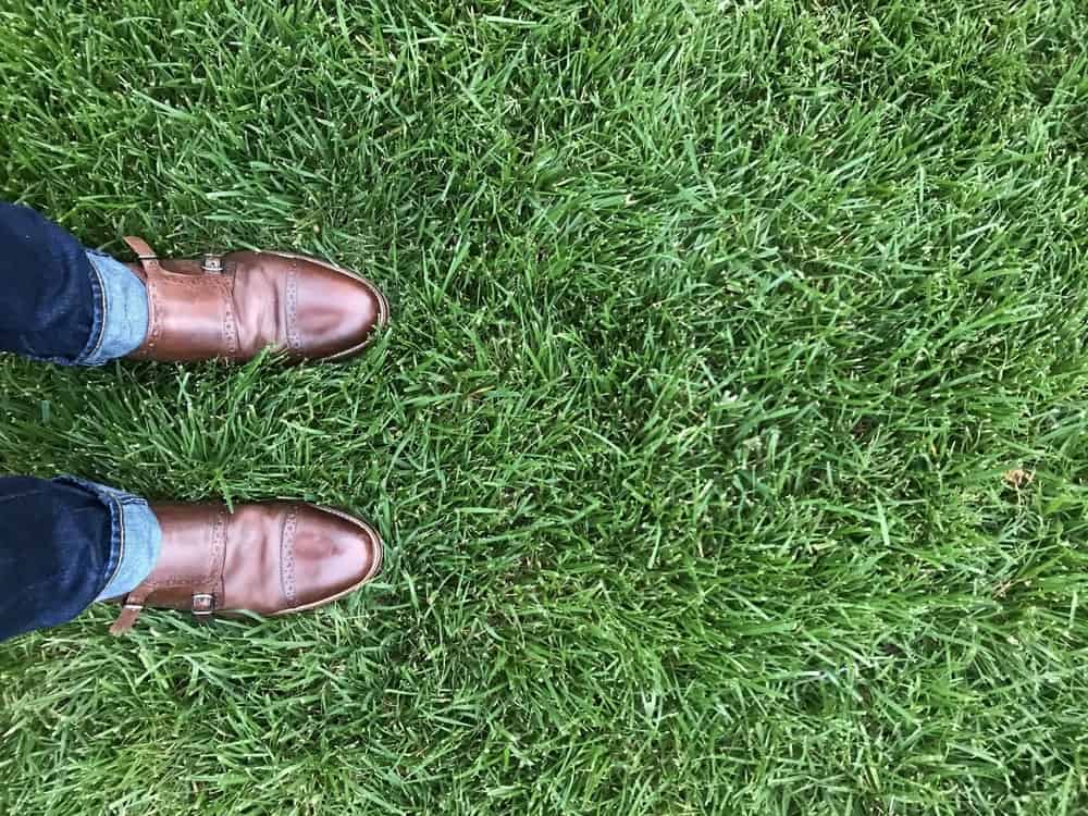 A close look at a man wearing brown leather monk-strap shoes with his jeans.