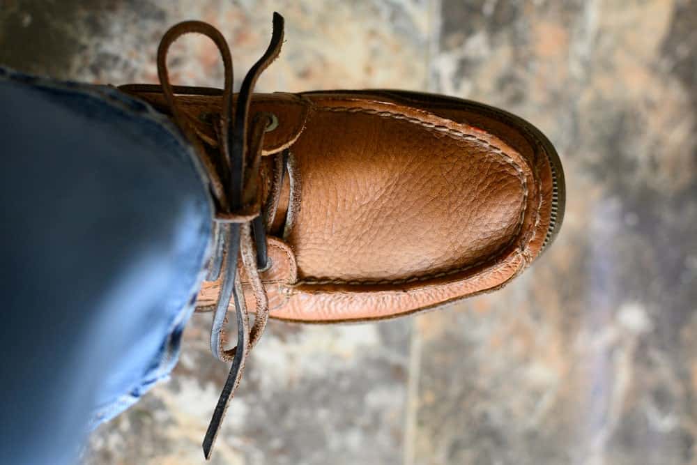 A close look at a man wearing brown leather boat shoes with his jeans.