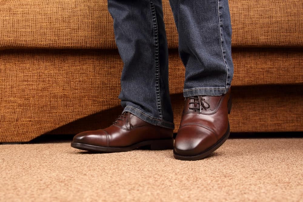 This is a close look at a man wearing jeans and a pair of oxford shoes.