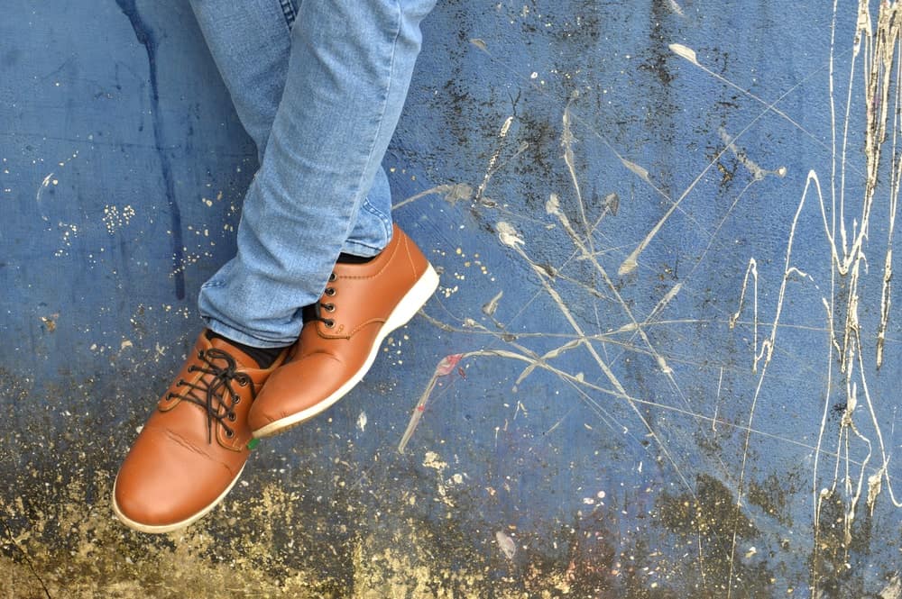 A close look at a man wearing brown leather shoes with his jeans.