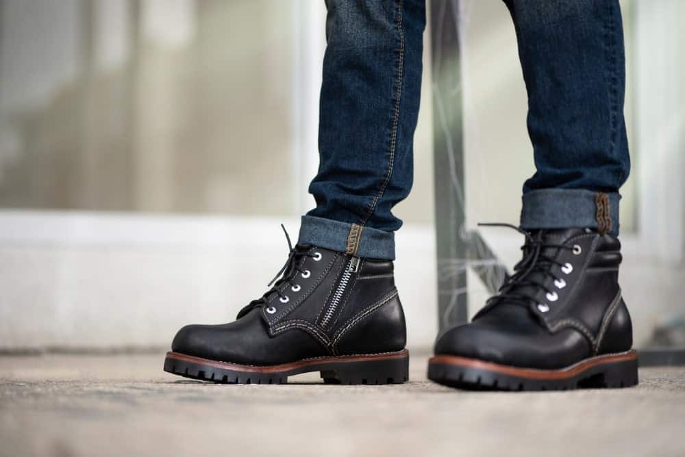 A close look at a man wearing boots with his jeans.